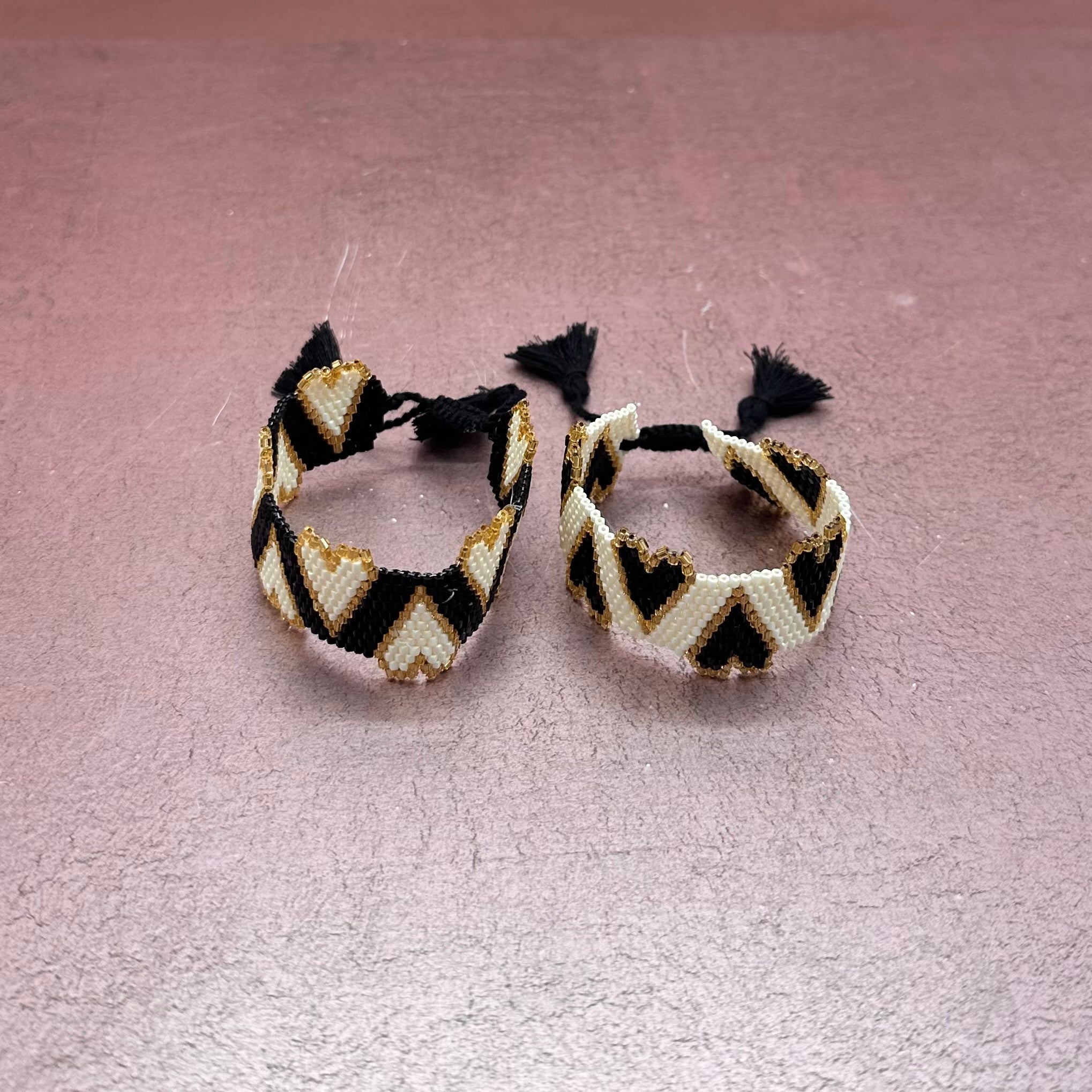 Beaded Bracelet White with Black Hearts Trimmed in Gold Tassel Closure